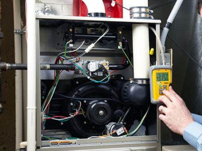 HVAC technician inspecting heating system components with a multimeter, emphasizing the importance of professional maintenance and repair for winter comfort.